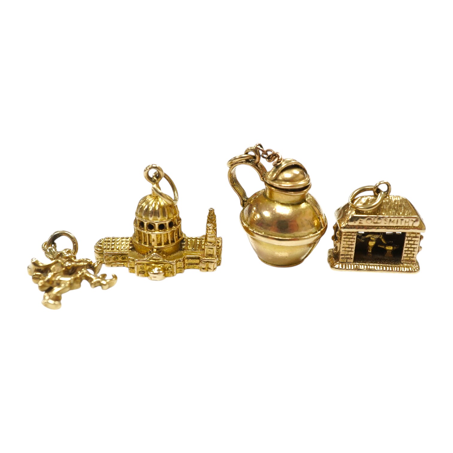 Three assorted 9ct gold charms, including Guernsey milk can and 'Ye Olde Smithy' and one other yellow metal charm, gross 14 grams. Condition - fair to good